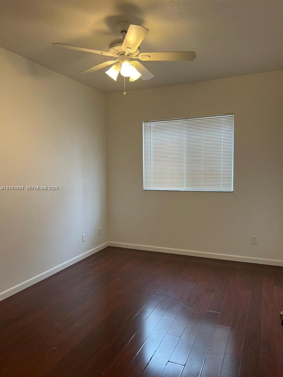 Room featuring wood-finish flooring, a multi-blade ceiling fan with integrated lighting, and horizontal window blinds