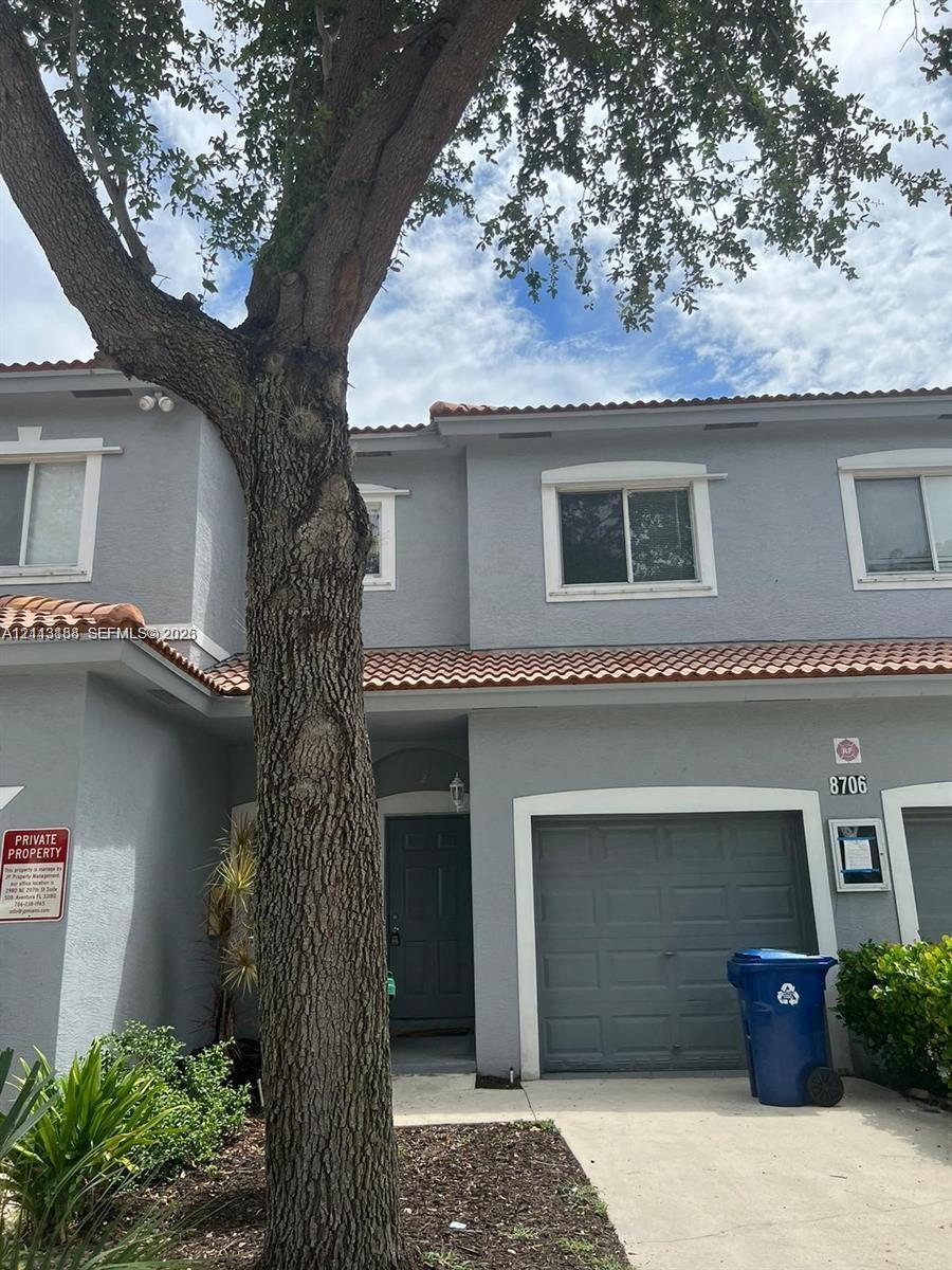 Two-story residence featuring a gray stucco exterior, tile roofing, an attached single-car garage, and concrete driveway