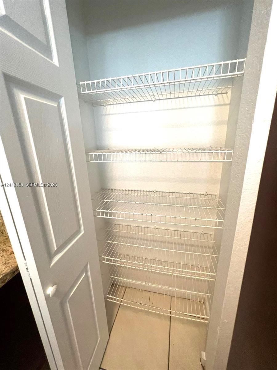 Storage closet featuring five tiered wire shelves and a painted paneled door