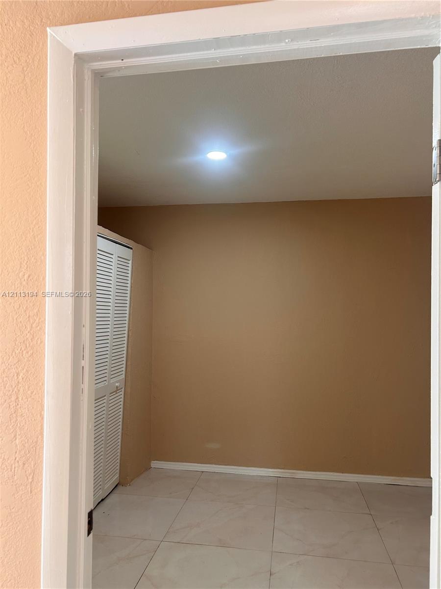 Interior space featuring neutral-toned walls, tile flooring, recessed ceiling lighting, and a white louvered closet door