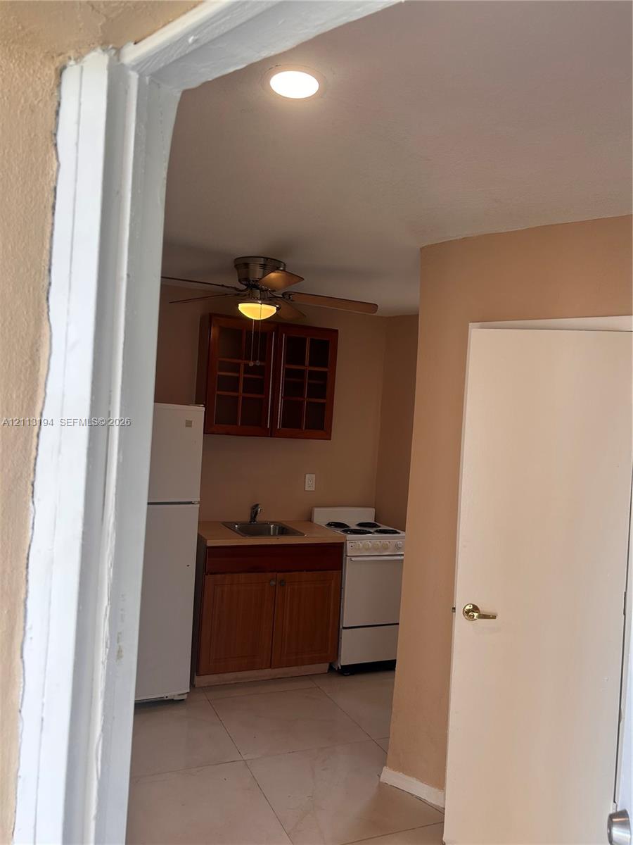 Kitchen featuring wood-finish cabinetry with glass-paneled upper doors, tile flooring, and integrated appliances Kitchen featuring wood-finish cabinetry with glass-paneled upper doors, tile flooring, and integrated appliances