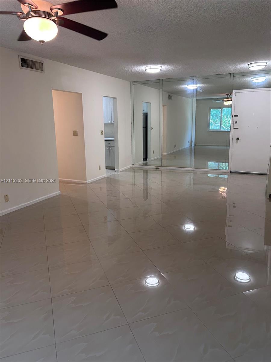 Large-format tile flooring, mirrored wall panels, and ceiling fan with integrated lighting