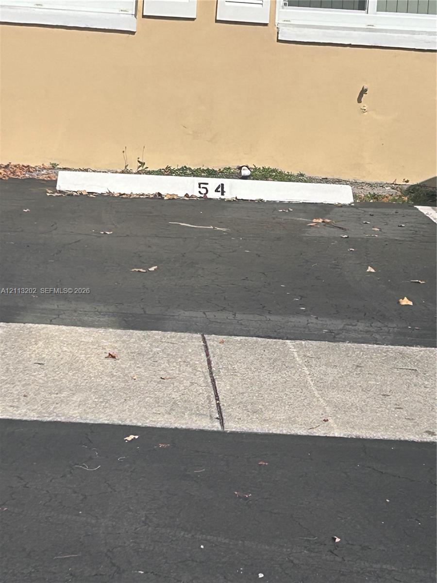 Designated parking space 54 with asphalt surfacing and concrete curbing