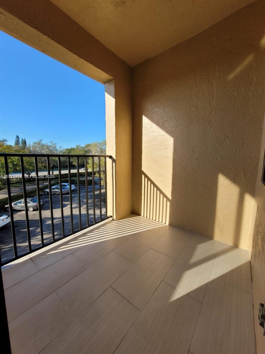 Covered balcony featuring tile flooring and a black metal railing
