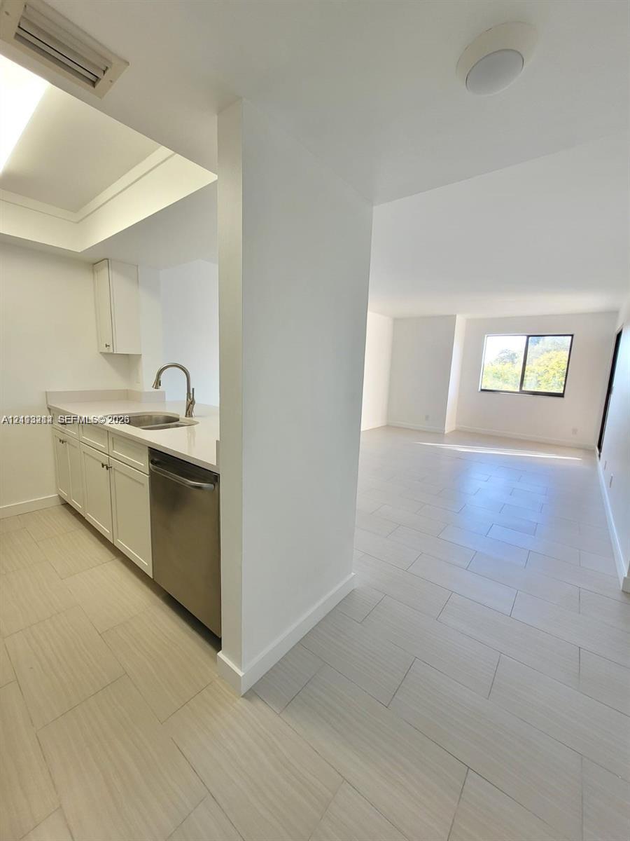 Kitchen featuring white cabinetry, solid-surface countertops, a stainless steel dishwasher, and a circular undermount sink
