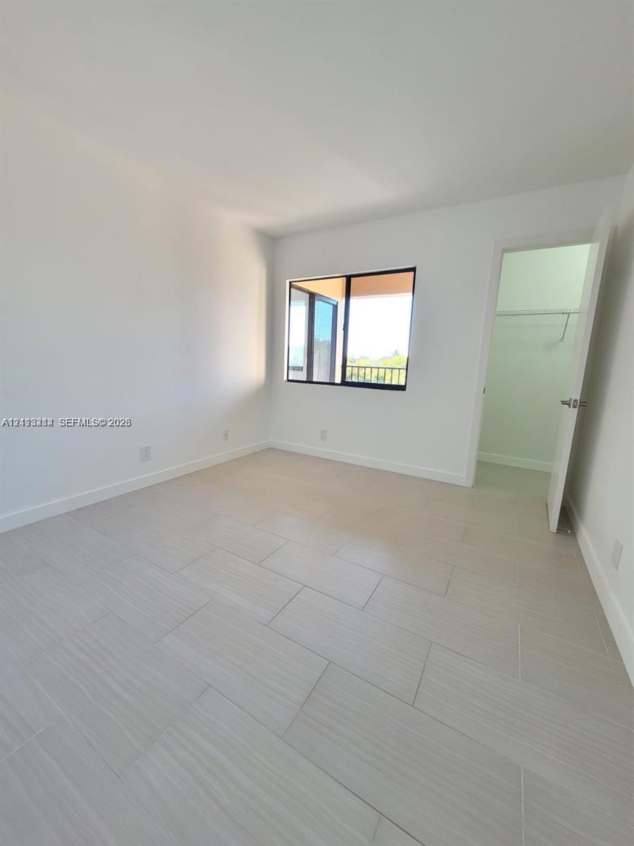 Neutral-toned tile flooring, light-filled interior, horizontal sliding window, and walk-in closet with built-in shelving