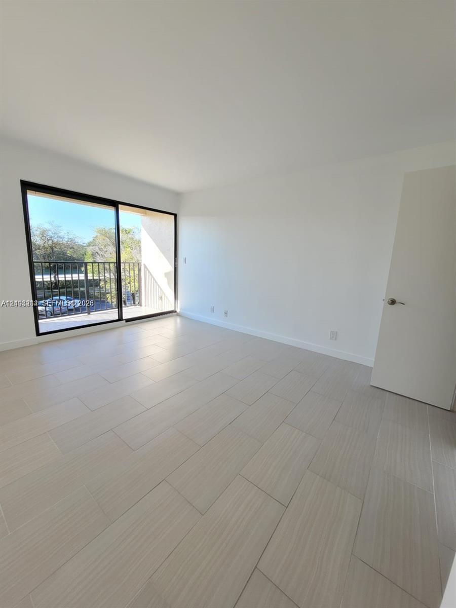 Neutral-toned porcelain tile flooring, large sliding glass door with a black frame, and exterior balcony with a metal railing