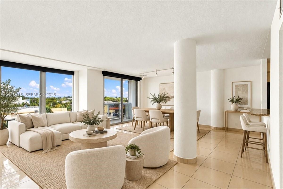 Open-concept floor plan featuring large floor-to-ceiling windows, ceramic tile flooring, architectural structural columns, and recessed track lighting
