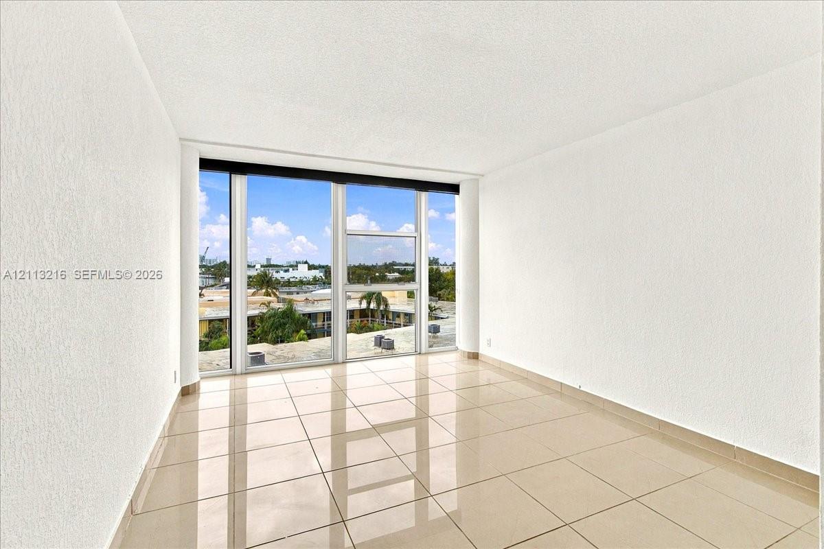 Floor-to-ceiling windows with exterior scenery, neutral tile flooring, and smooth-finish walls