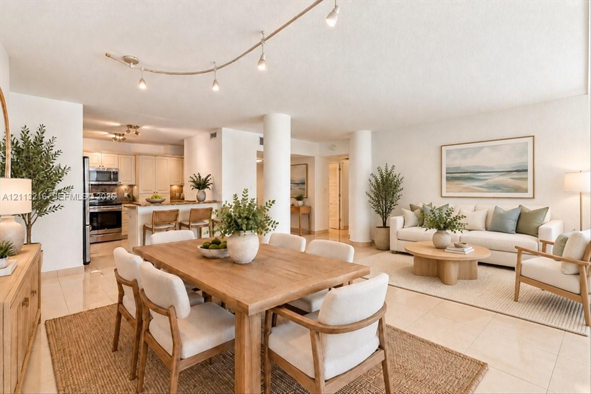 Open-concept living space featuring high-gloss tile flooring, structural architectural columns, adjustable track lighting, and a breakfast bar