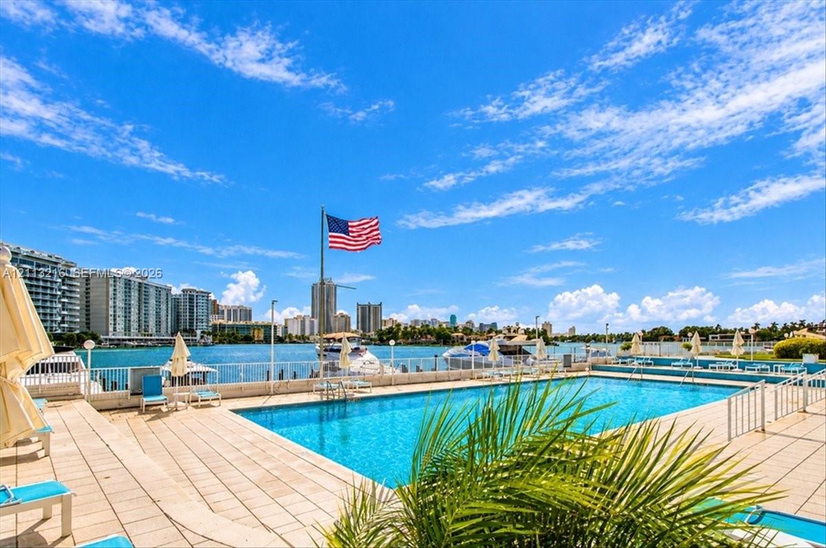 Swimming pool featuring stone-paved decking, metal perimeter fencing, and water-front placement