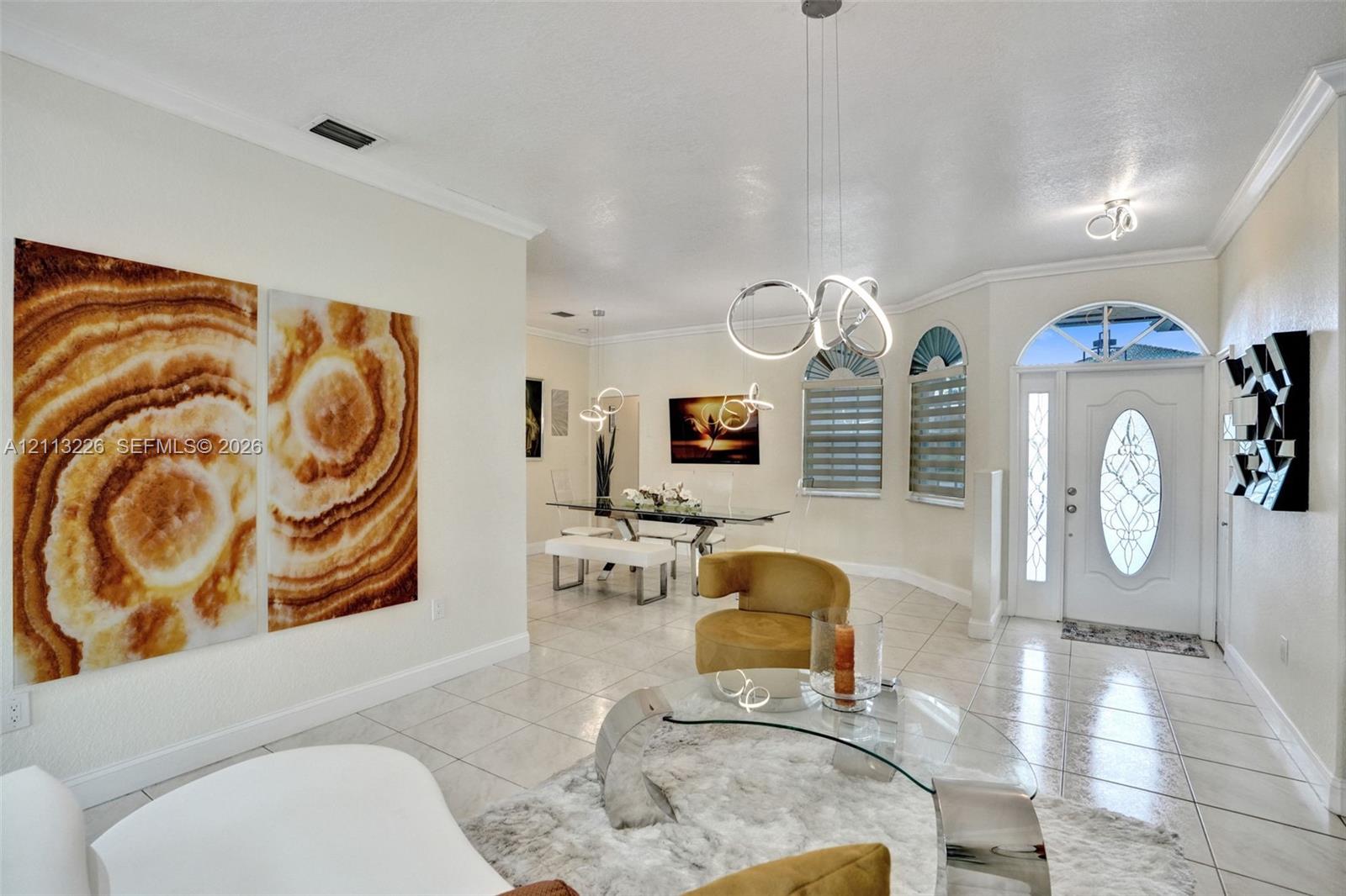 Entryway featuring tile flooring, arched windows, an oval glass-paneled front door, and modern multi-ring pendant lighting