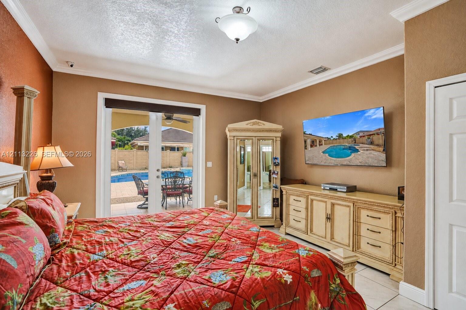 Room featuring crown molding, recessed lighting, tile flooring, and glass-paned double doors leading to a patio with a swimming pool