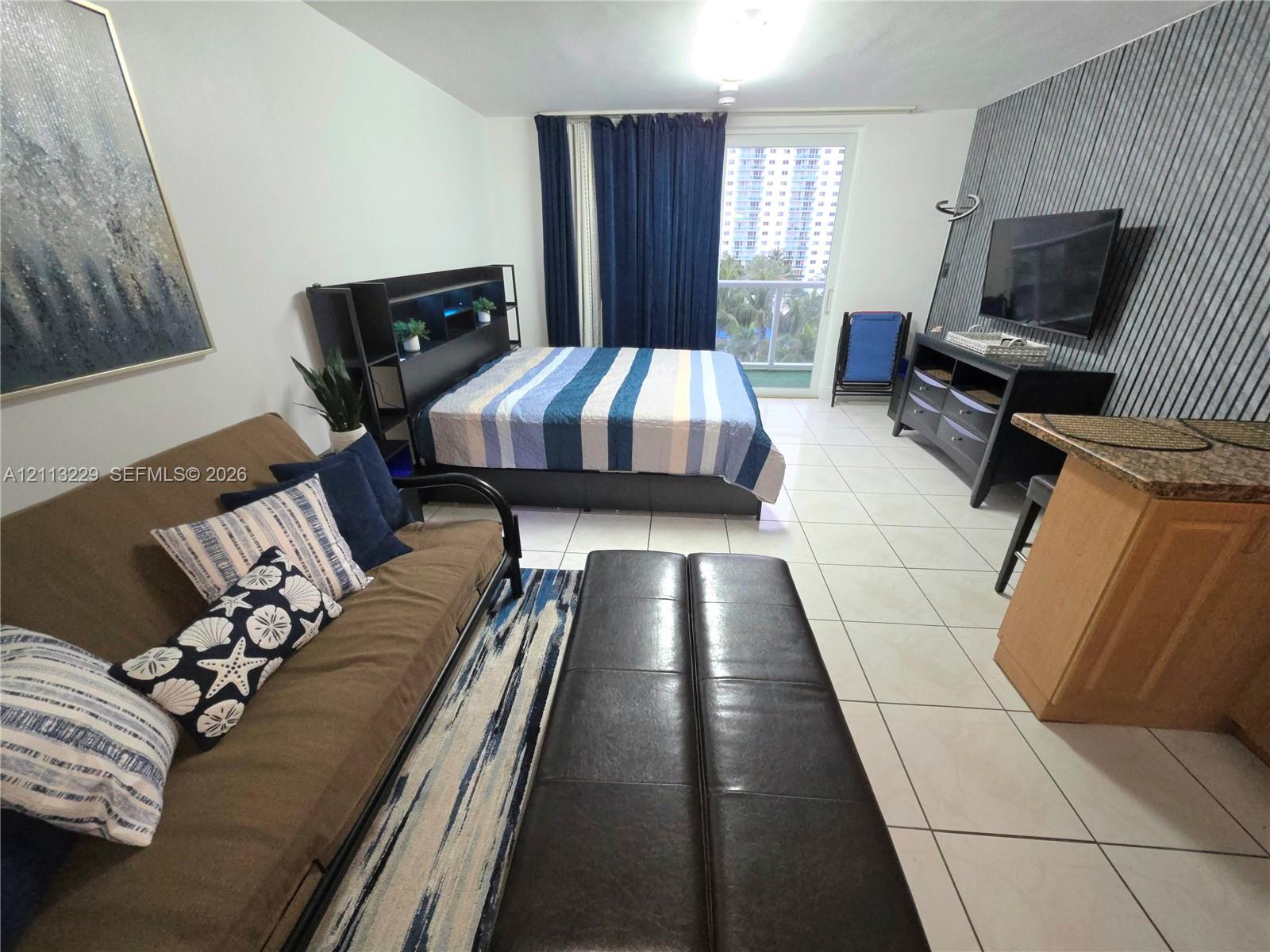 Ceramic tile flooring, textured accent wall, and sliding glass door with balcony access Ceramic tile flooring, textured accent wall, and sliding glass door with balcony access