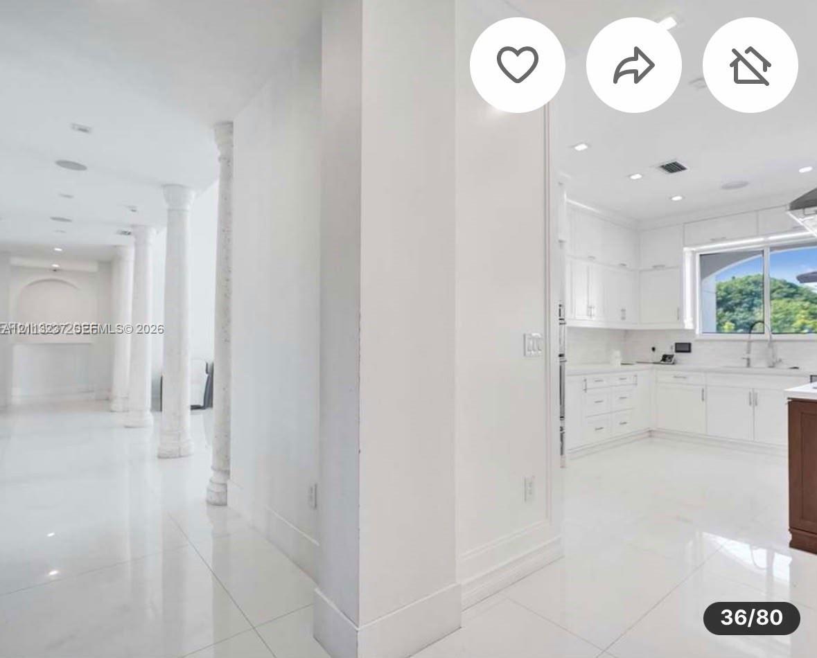 Interior featuring structural columns, polished stone flooring, recessed lighting, white shaker-style cabinetry, and integrated kitchen appliances
