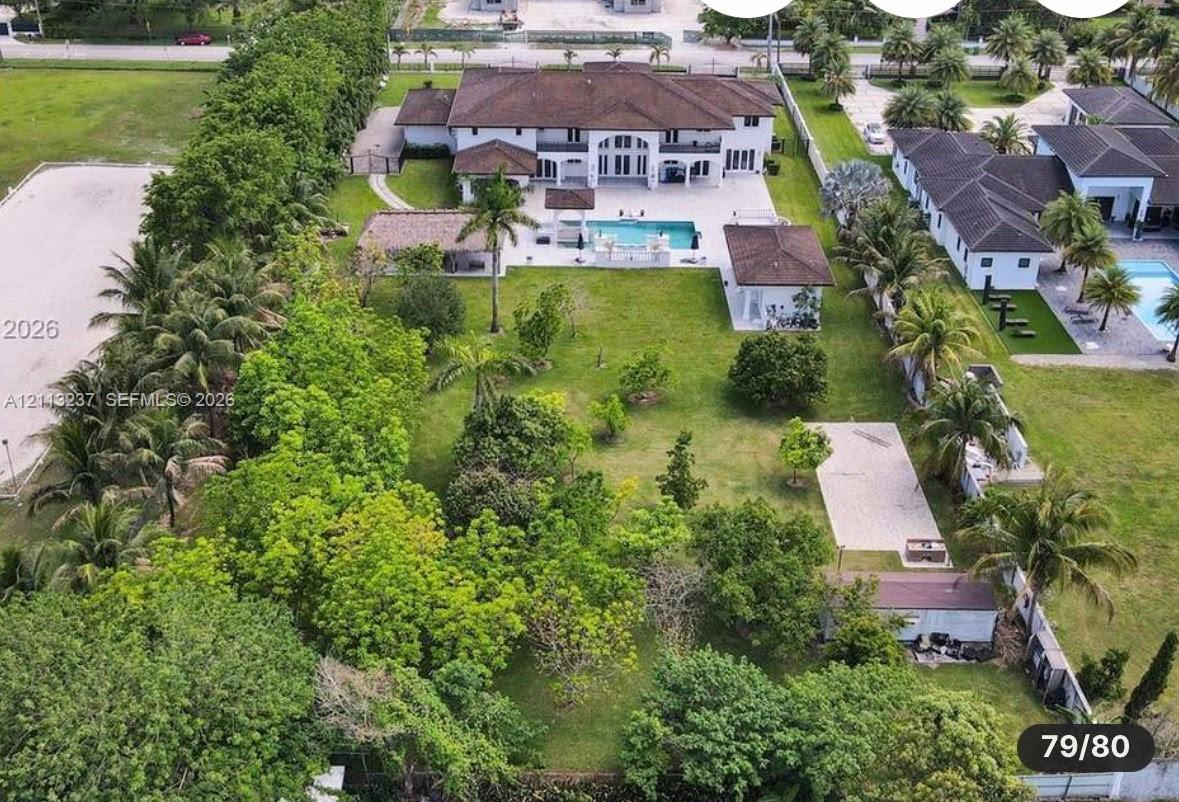 Expansive estate grounds featuring a multi-structure layout, a paved pool deck, a private swimming pool, and mature perimeter landscaping