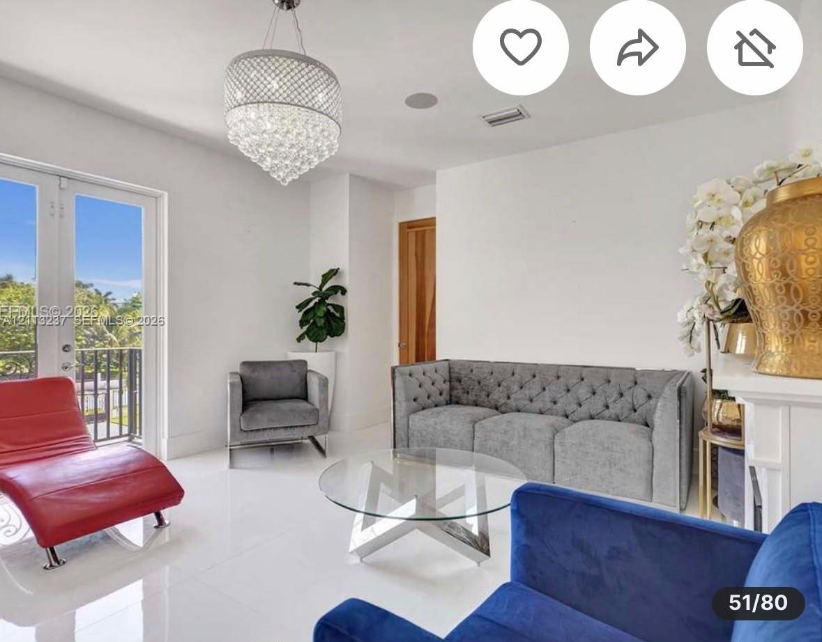 Large-format porcelain tile flooring, ornate crystal chandelier, and glass-paned double doors with black metal railing