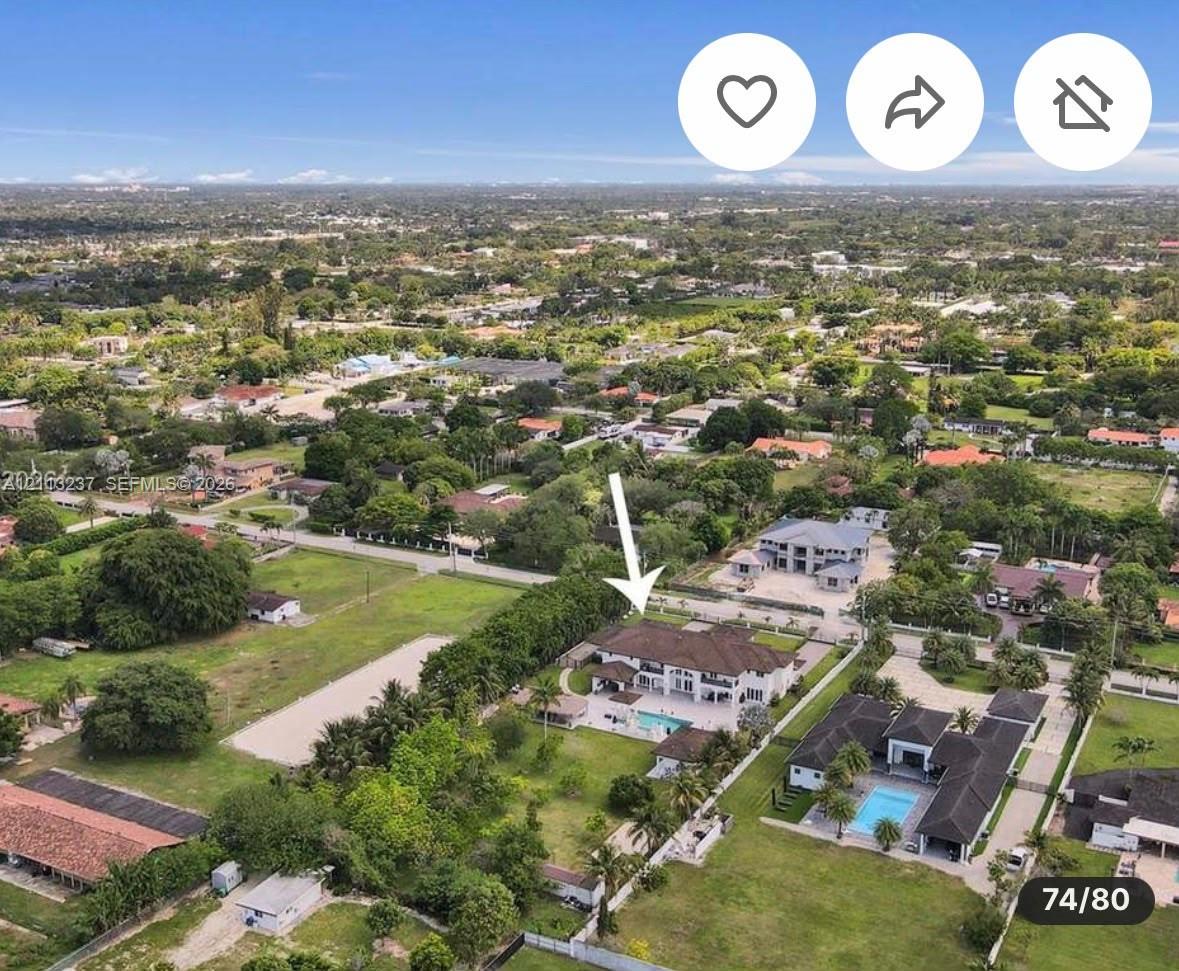 Aerial perspective of a multi-story residence featuring a tile roof, an expansive swimming pool, a covered patio, and large private acreage