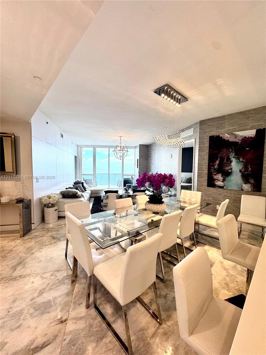 Polished stone flooring, textured stone accent wall, floor-to-ceiling glass paneling, and custom integrated lighting fixtures