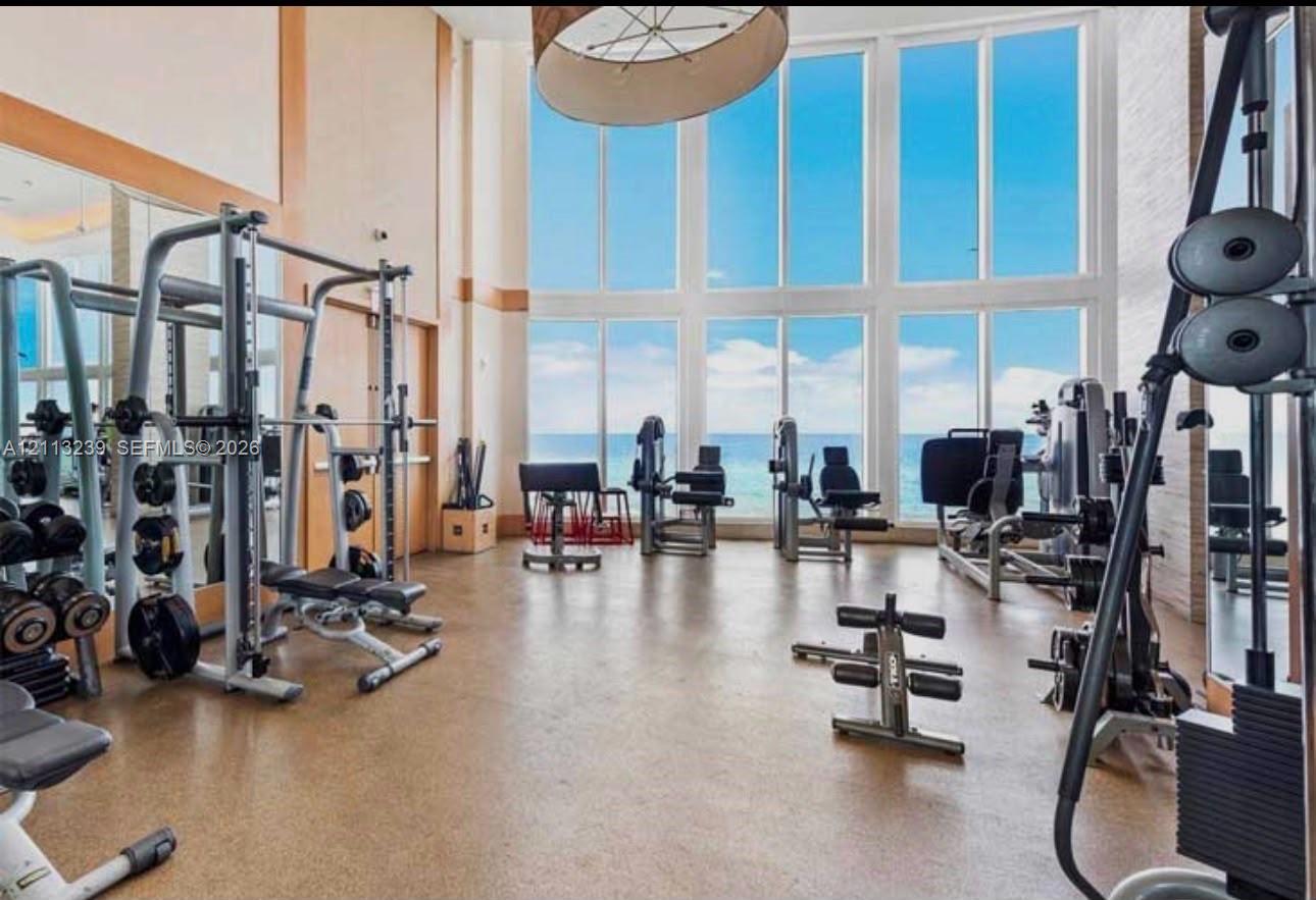 Fitness area featuring floor-to-ceiling windows, high ceilings, large-format tile flooring, and wall-to-wall mirrors
