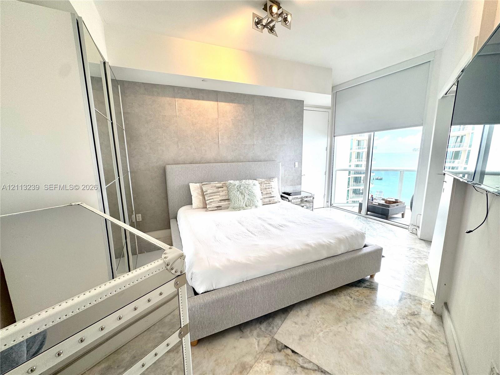 Floor-to-ceiling sliding glass doors, marble flooring, textured accent wall, and built-in mirrored wardrobe