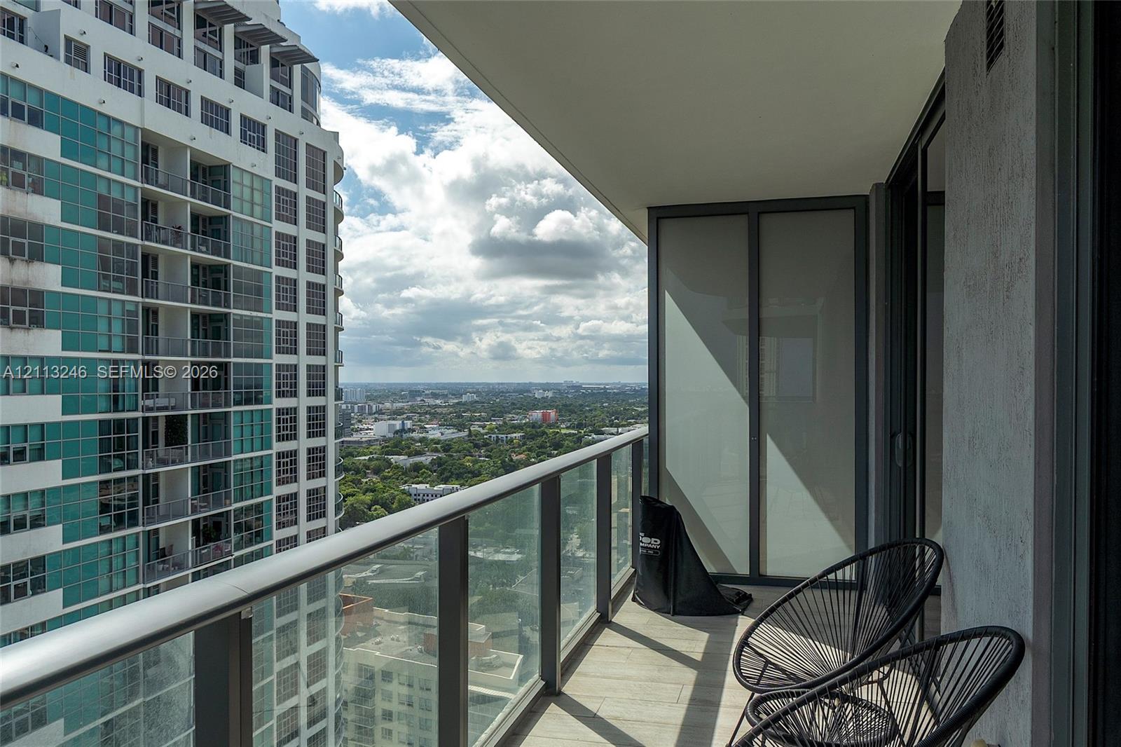 Covered balcony featuring a glass panel railing, tile flooring, and frosted privacy screen