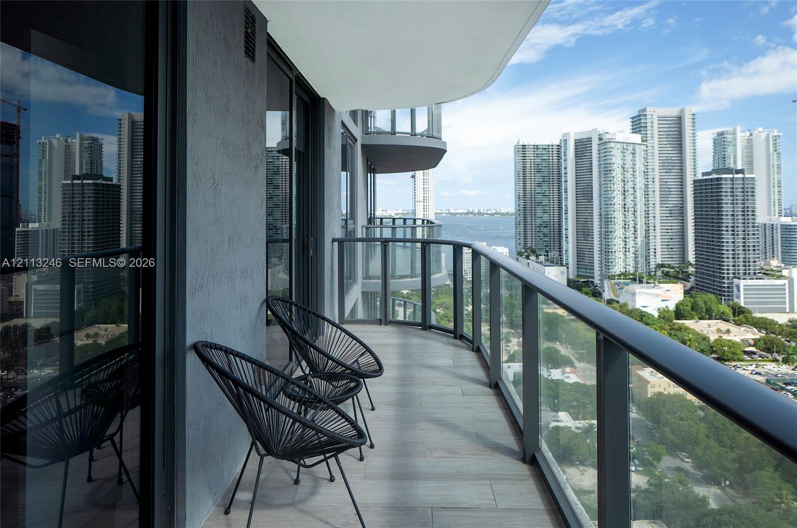 Covered balcony featuring tile flooring and glass panel railings with metal framing