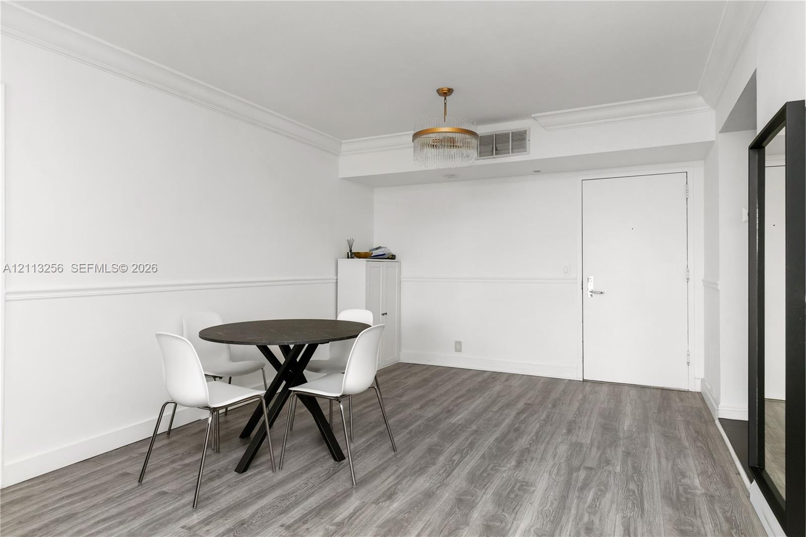 Wood-finish flooring, crown molding, chair rail trim, and a gold-tone drum chandelier Wood-finish flooring, crown molding, chair rail trim, and a gold-tone drum chandelier