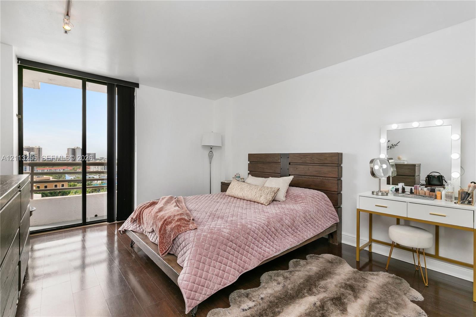 Wood-finish flooring, floor-to-ceiling sliding glass doors, and a private balcony