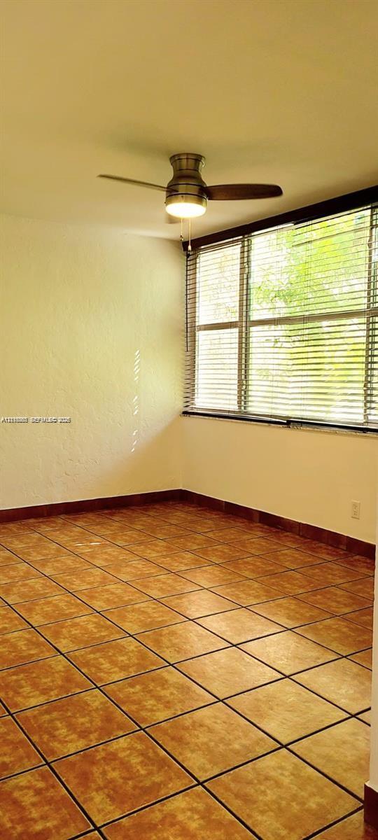 Large-format tile flooring, multi-pane windows, and a ceiling fan with integrated lighting