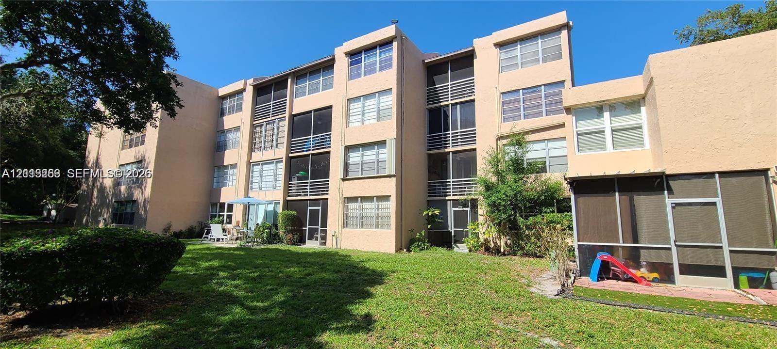 Multi-story stucco exterior featuring screened-in lanais, grid-pattern windows, and landscaped grounds Multi-story stucco exterior featuring screened-in lanais, grid-pattern windows, and landscaped grounds