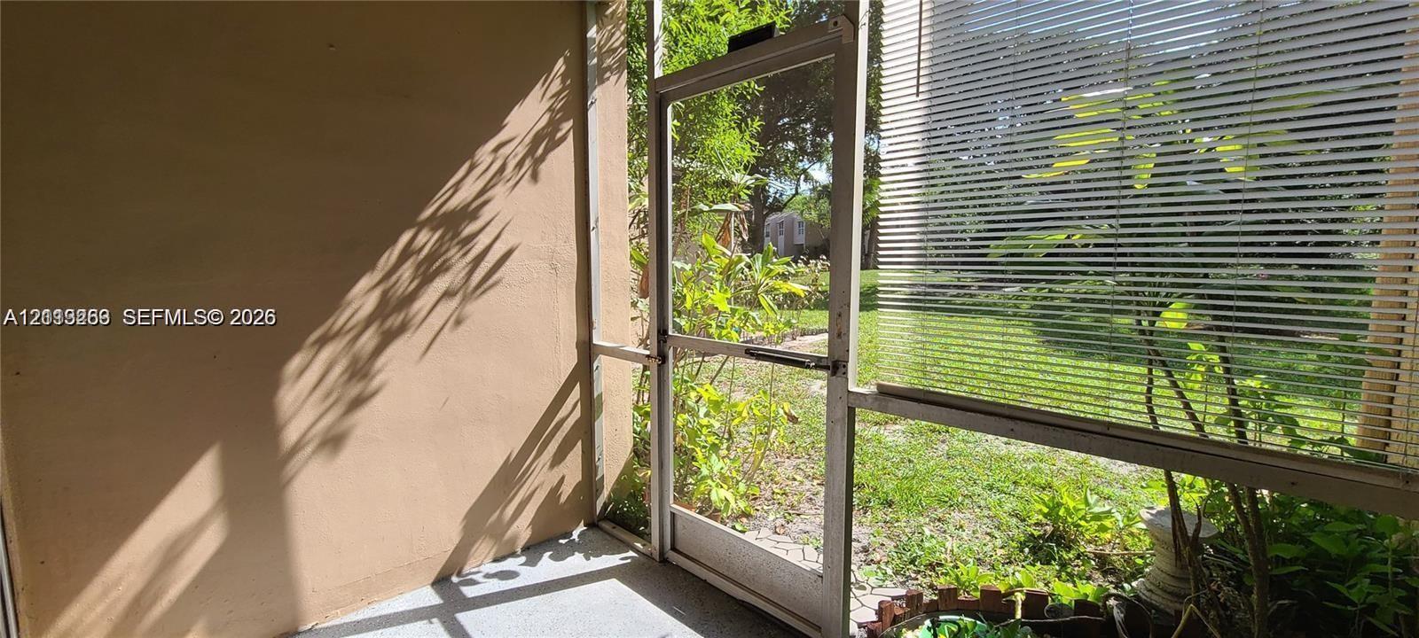 Enclosed patio featuring a concrete floor, solid wall construction, and a screen door with metal framing
