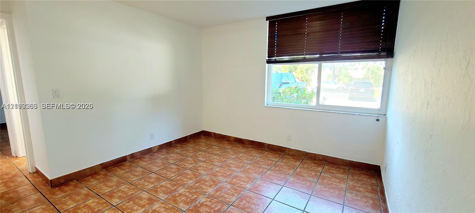 Room featuring ceramic tile flooring, neutral wall finishes, and a window equipped with horizontal slat blinds