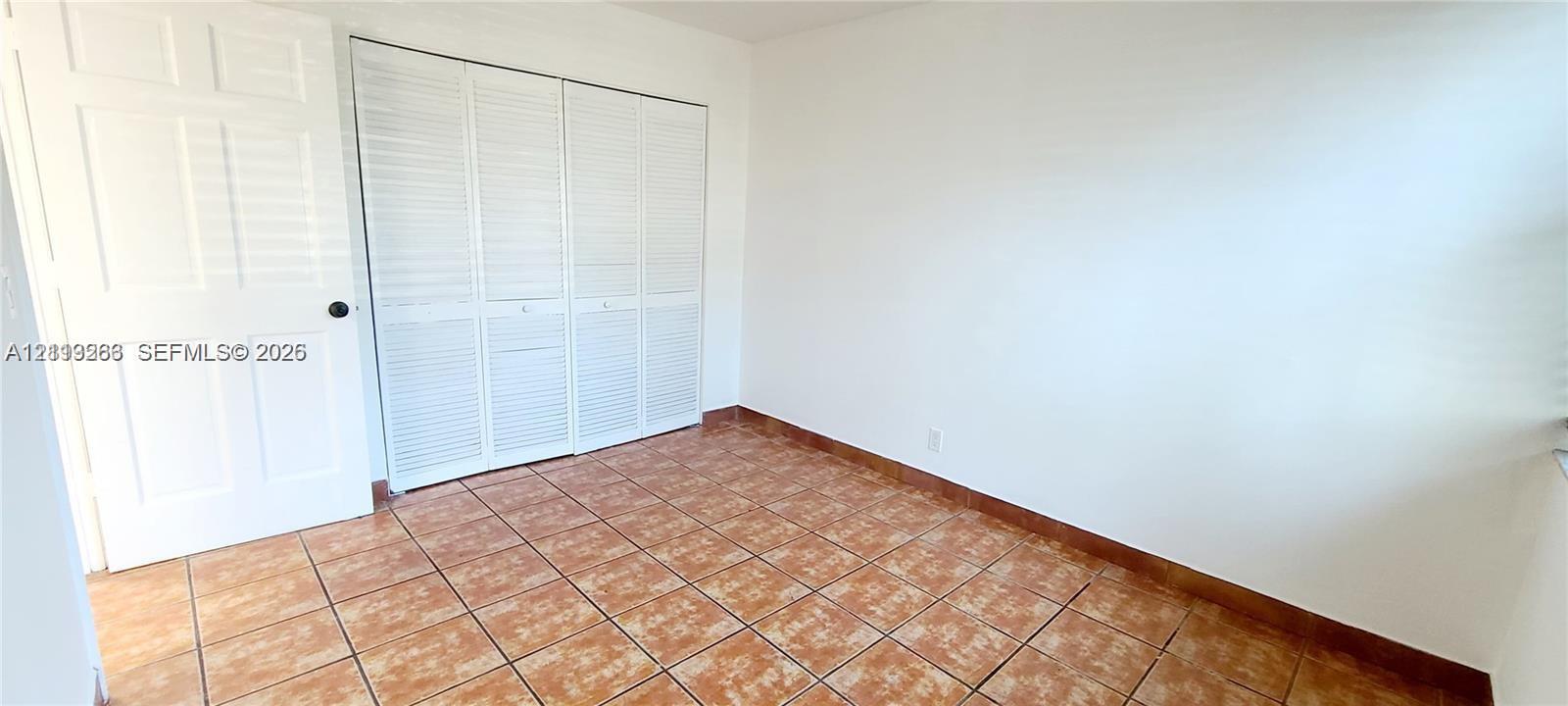 Interior space featuring neutral wall paint, tile flooring, and bi-fold closet doors