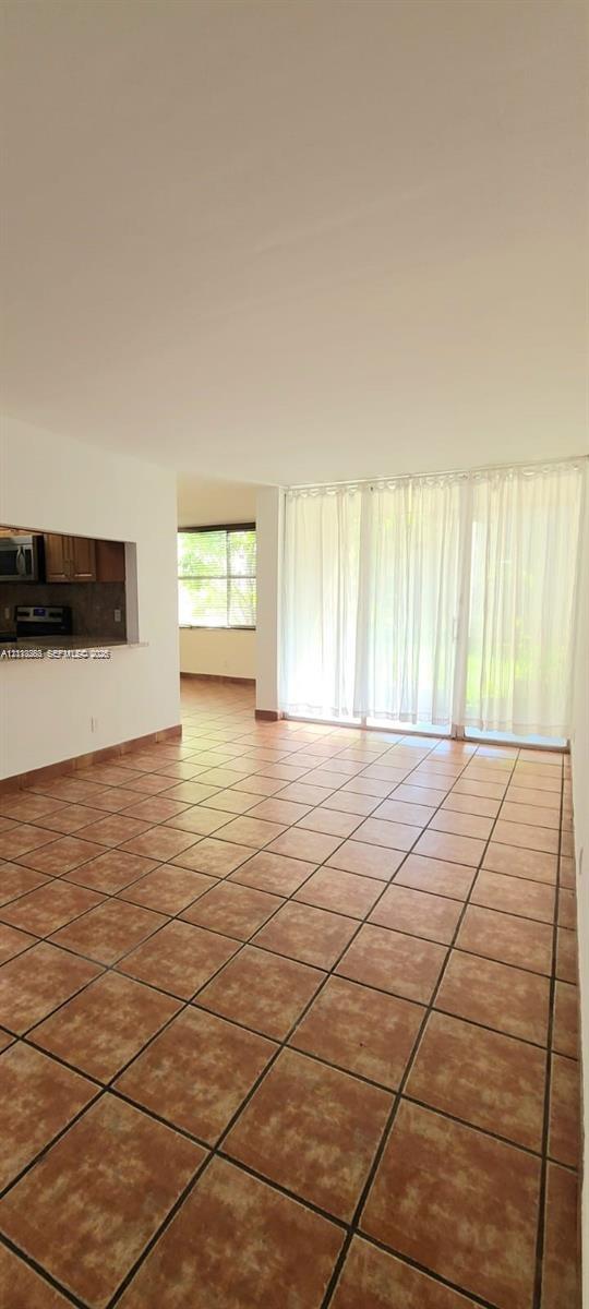 Ceramic tile flooring throughout, expansive wall-to-wall sliding glass doors, and a kitchen pass-through window