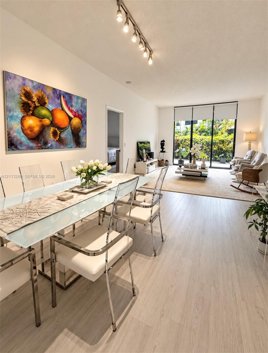 Living area featuring wood-finish flooring, floor-to-ceiling black-framed glass sliding doors, and neutral wall tones Living area featuring wood-finish flooring, floor-to-ceiling black-framed glass sliding doors, and neutral wall tones