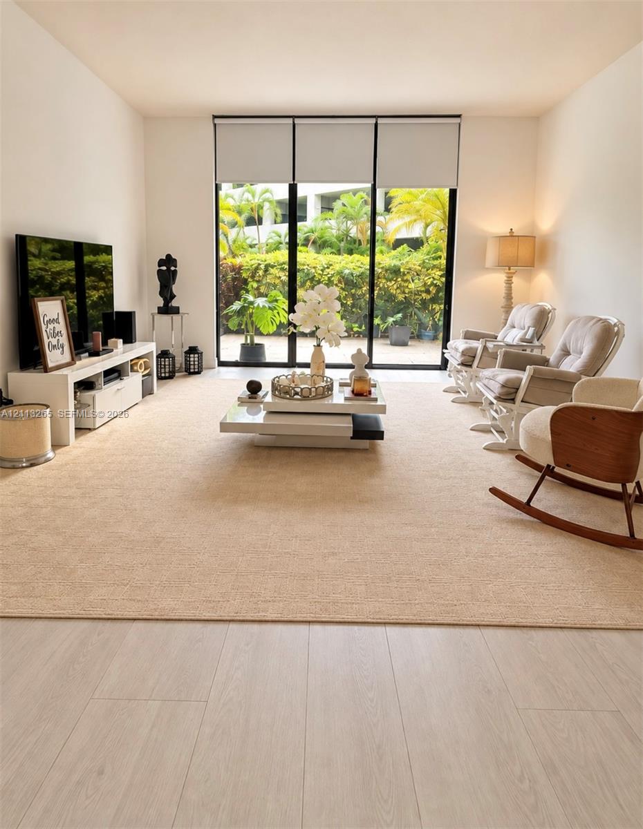 Floor-to-ceiling sliding glass door with sheer drapery and wood-finish flooring Floor-to-ceiling sliding glass door with sheer drapery and wood-finish flooring