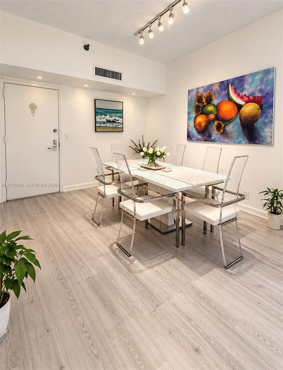 Kitchen featuring white shaker-style cabinetry, dark stone countertops, stainless steel appliances, a glass-front upper cabinet, and light-toned tile flooring