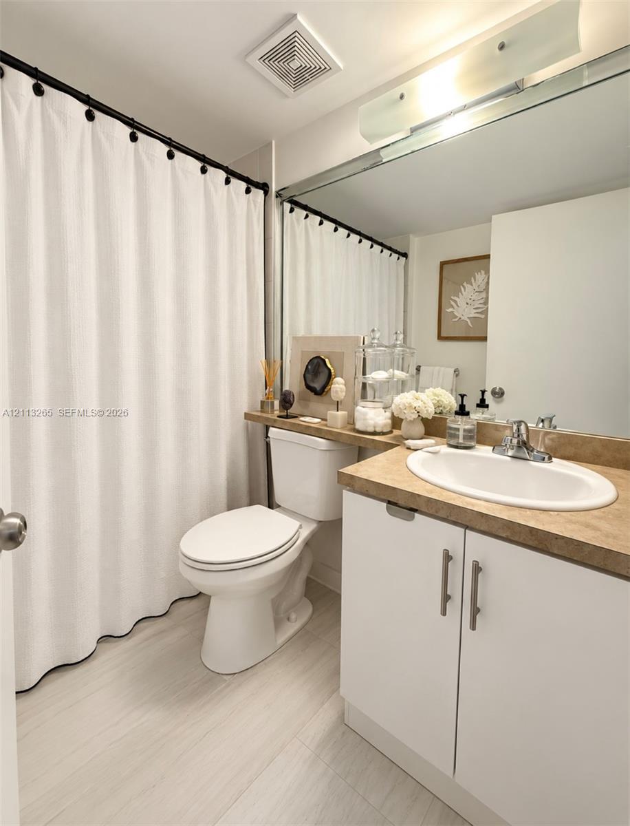 Stackable white laundry unit housed in a closet featuring white louvered doors