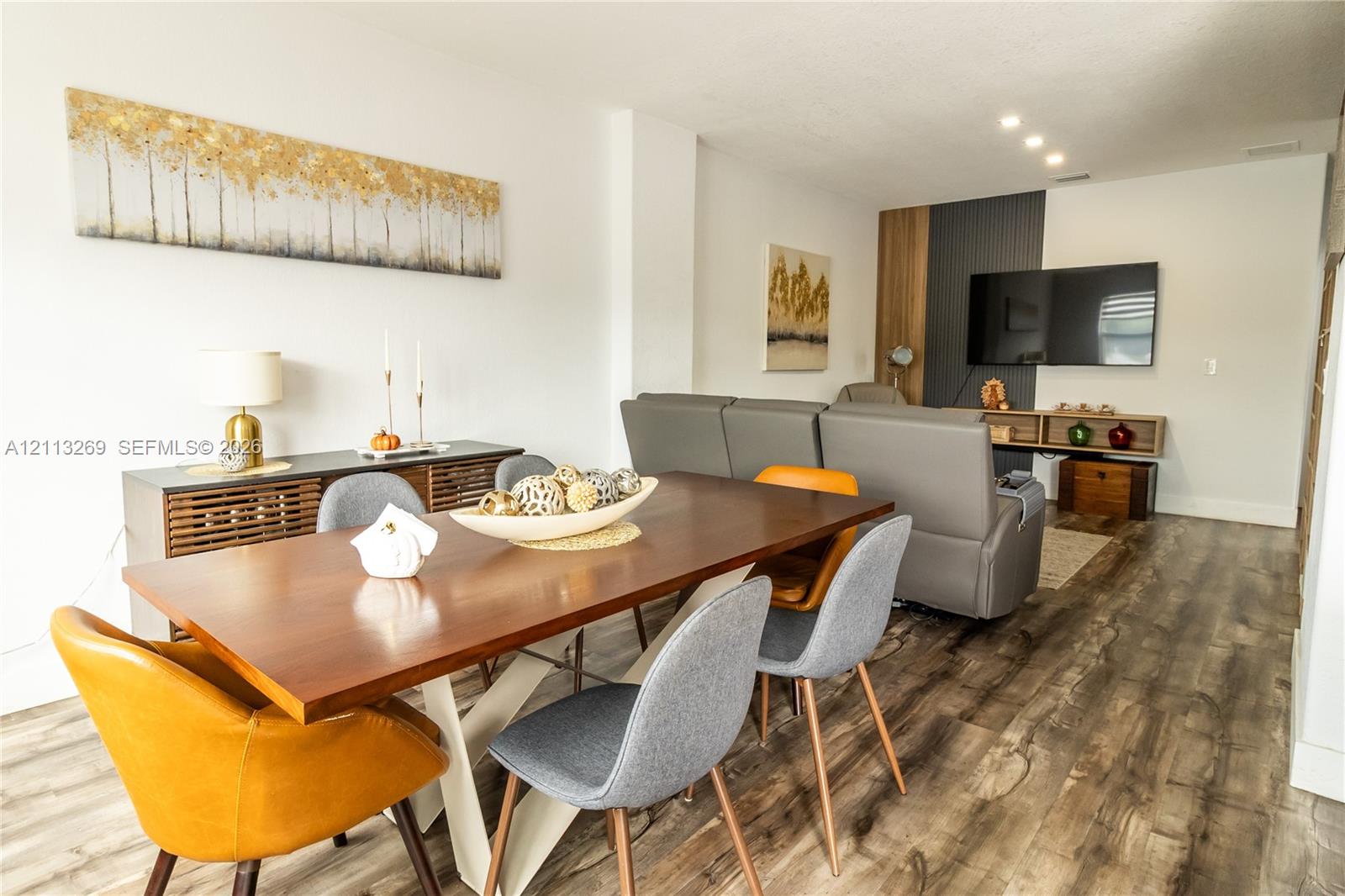 Wood-finish flooring, recessed lighting, and a vertical wood and charcoal paneled accent wall