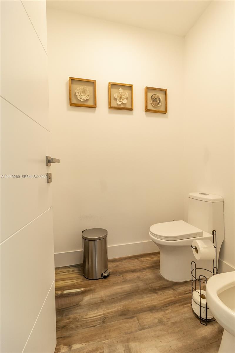 Wood-finish flooring, dual-flush toilet, and solid-core interior door with satin nickel hardware