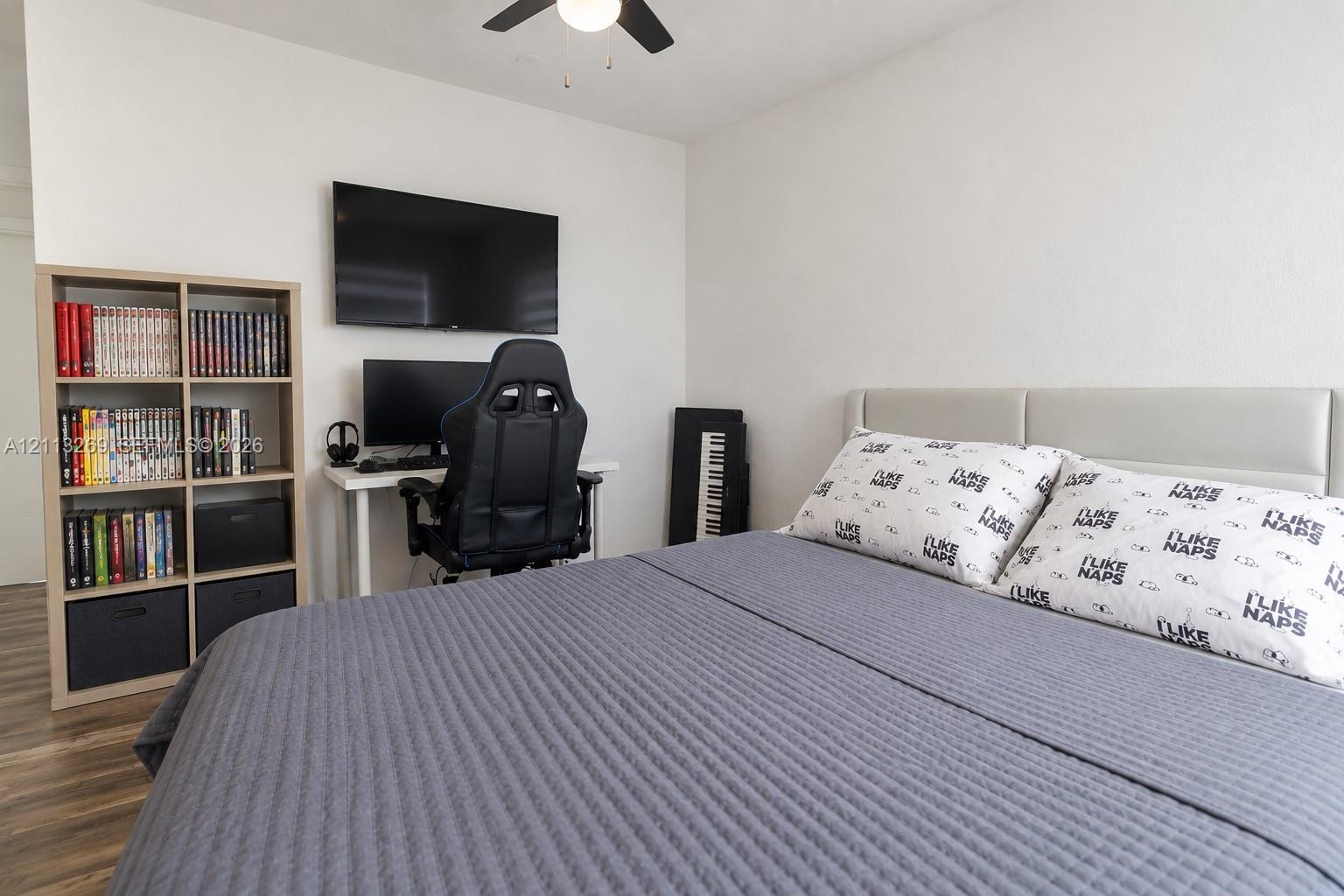 Wood-finish flooring, neutral walls, and a ceiling fan with integrated lighting