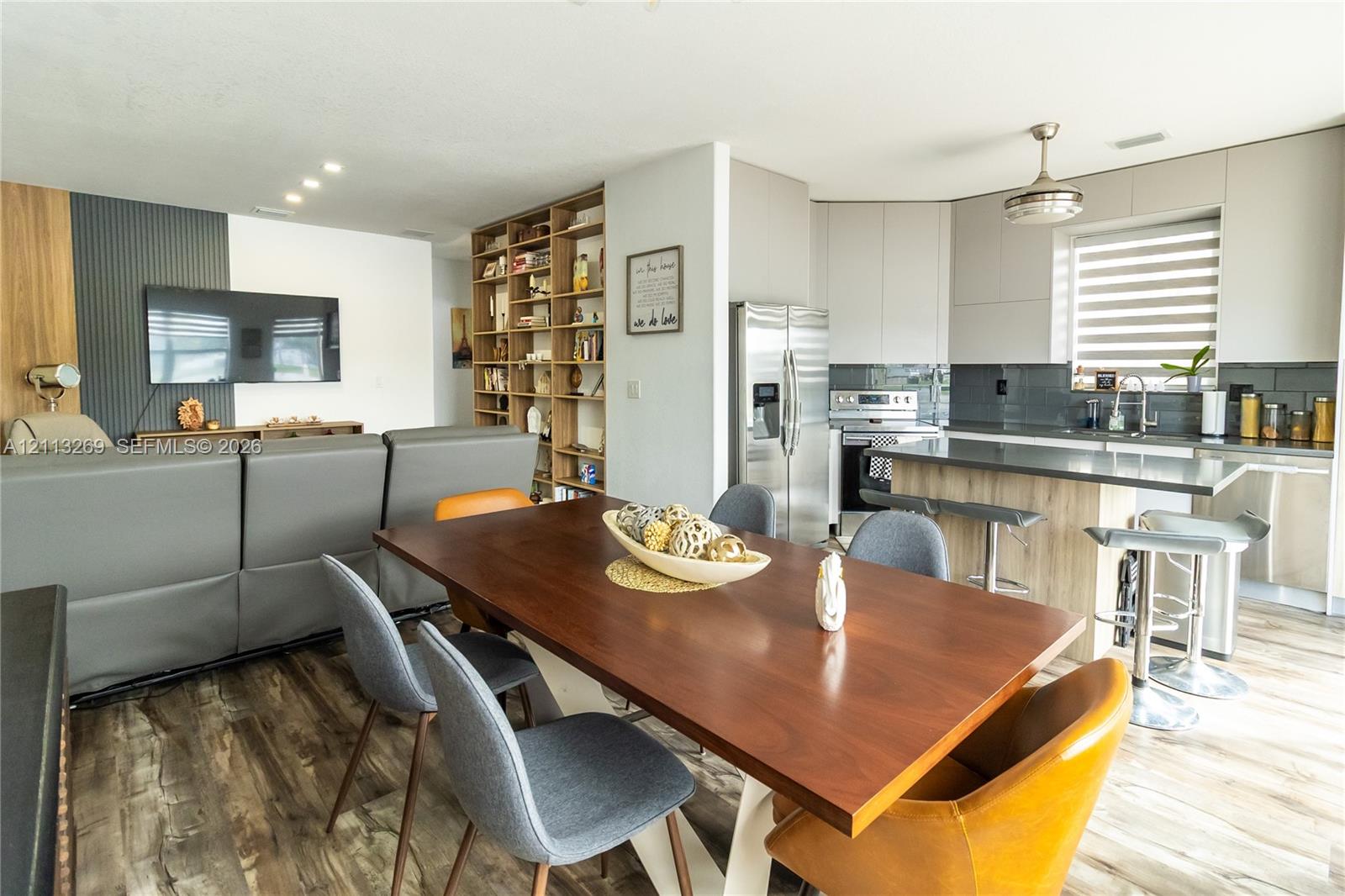 Kitchen featuring flat-panel cabinetry, a wood-finish island, and stainless steel appliances, accented by floor-to-ceiling built-in shelving and wood-finish flooring
