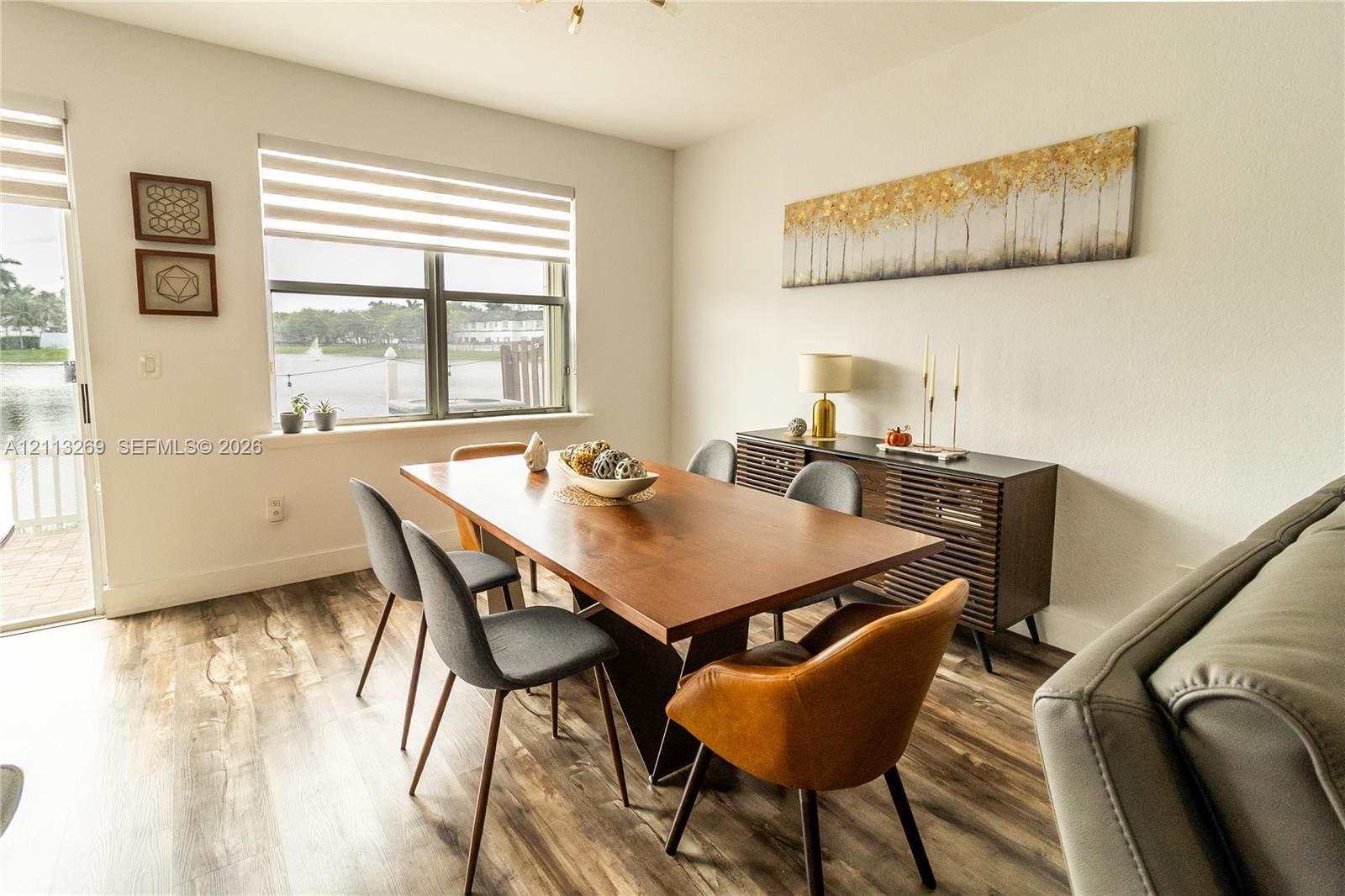 Wood-finish flooring, large window with horizontal blinds, glass sliding door, and neutral wall tones