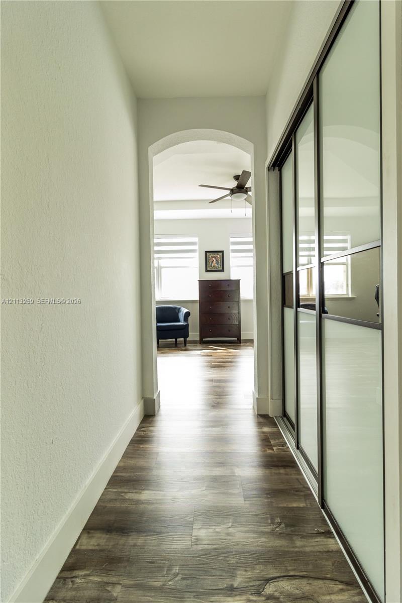 Arched pass-through featuring wood-finish flooring and floor-to-ceiling sliding closet doors with frosted glass panels