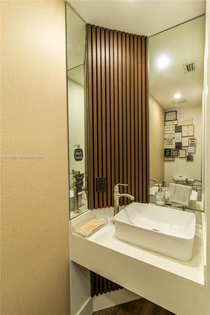 Wall-mounted vanity featuring a white rectangular vessel sink, metallic faucet, full-height decorative wood slat paneling, and mirrored corner walls