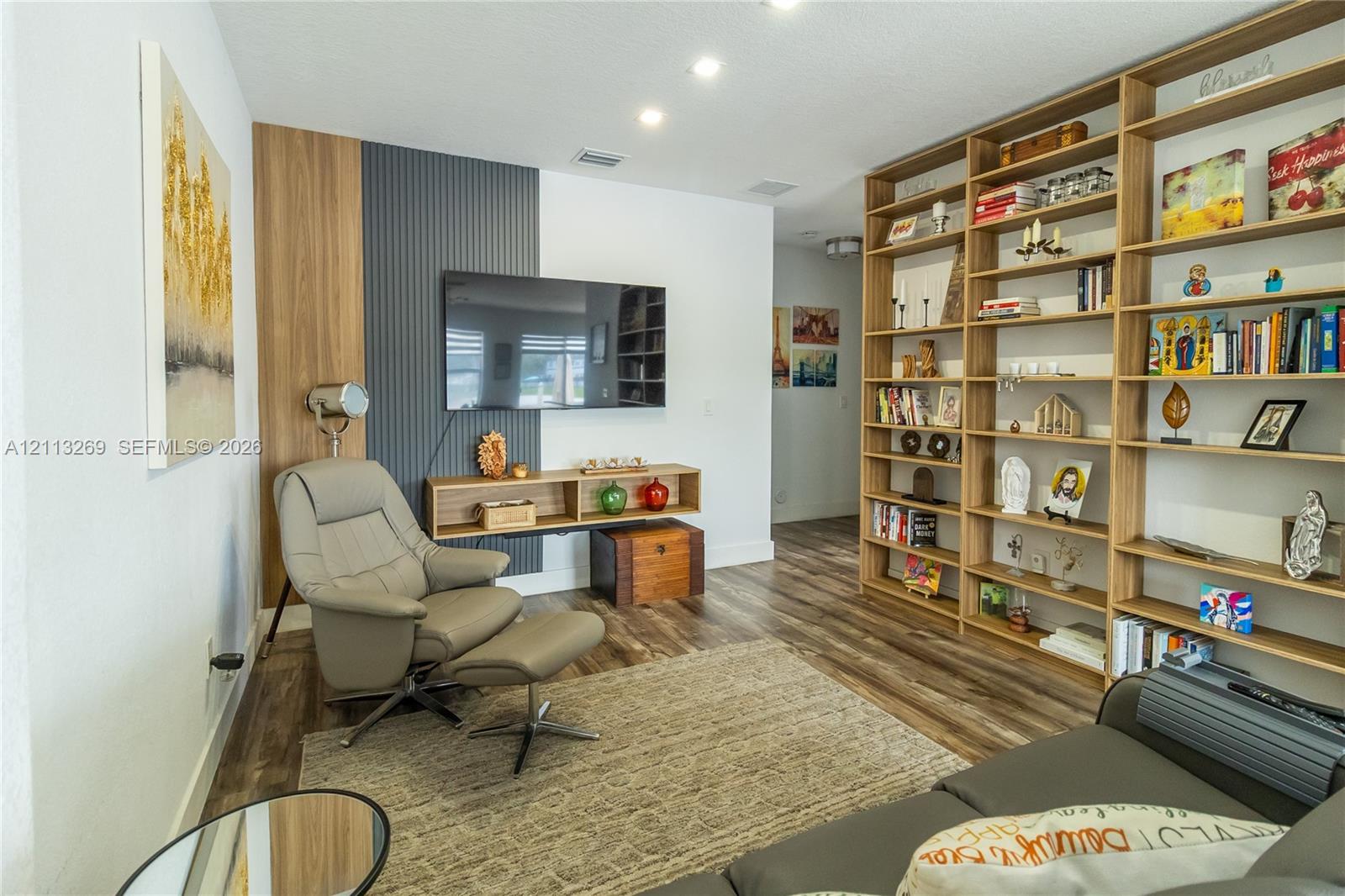 Custom floor-to-ceiling built-in shelving, wood-finish flooring, and a decorative accent wall featuring vertical slat paneling and wood trim