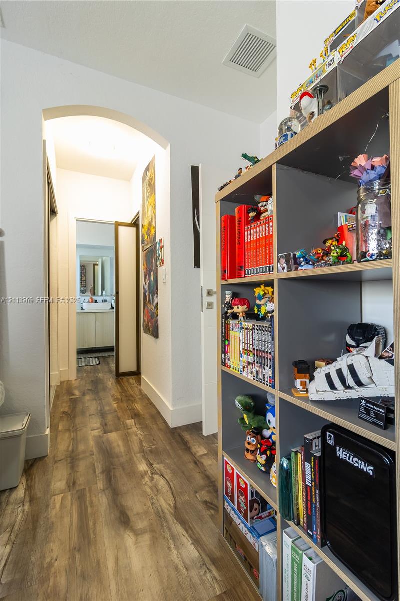Hallway featuring wood-finish flooring and a prominent arched entryway