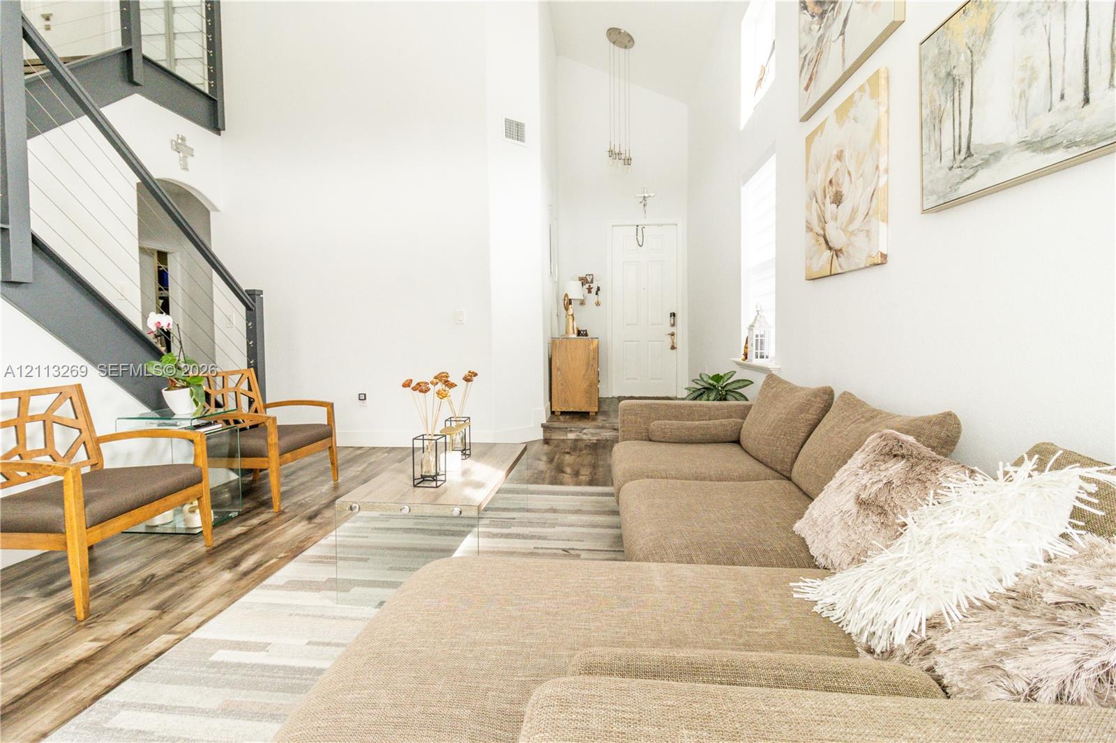 Vaulted ceilings, staircase with cable railing, wood-finish flooring, and multi-pane front door