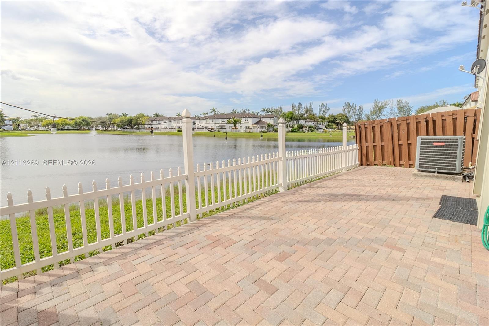Paver patio with a white picket fence, overlooking a water feature